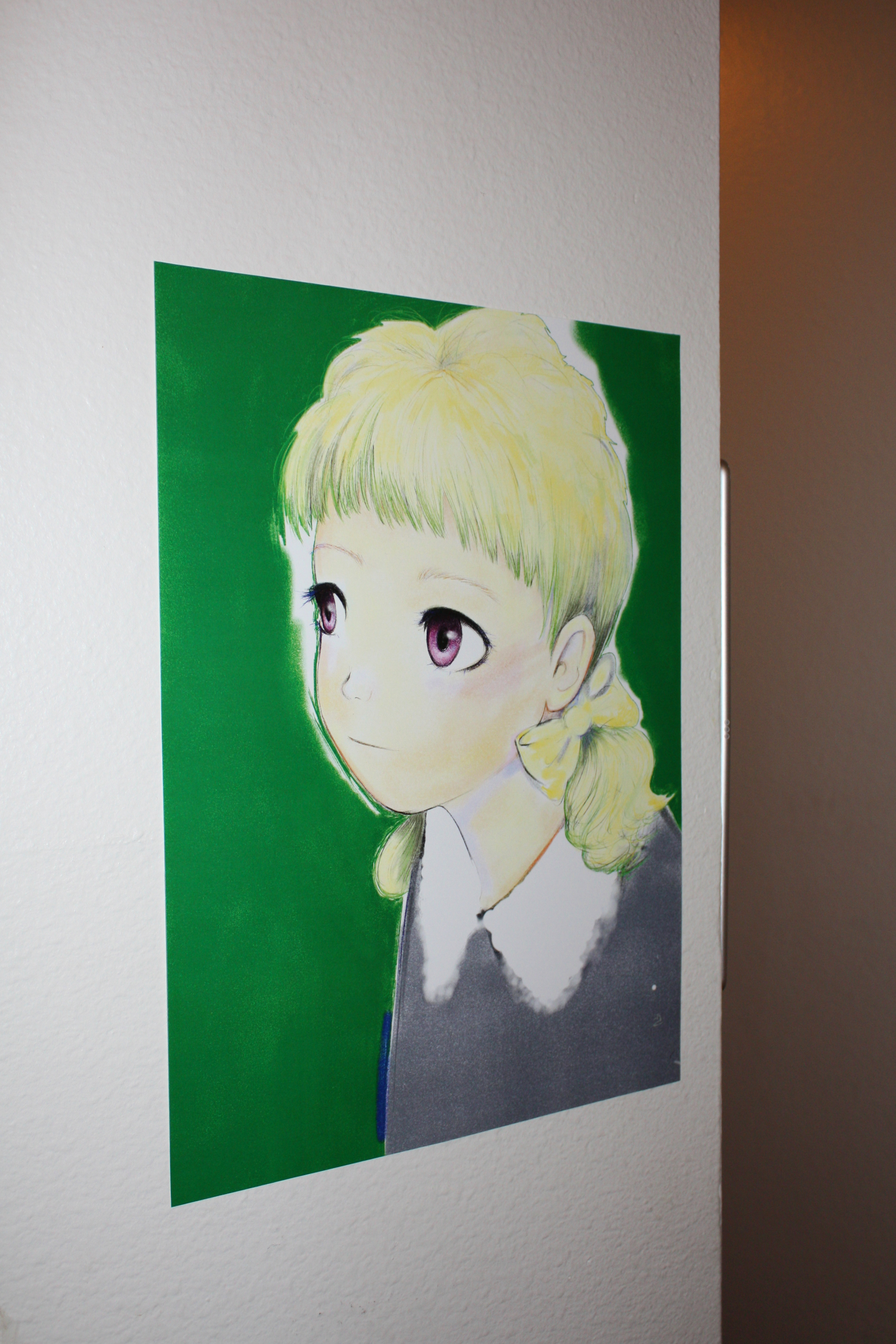 Detail of an anime girl with blonde hair hung on a white wall